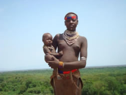 A Kara woman cradling a small child at the bank of Omo River